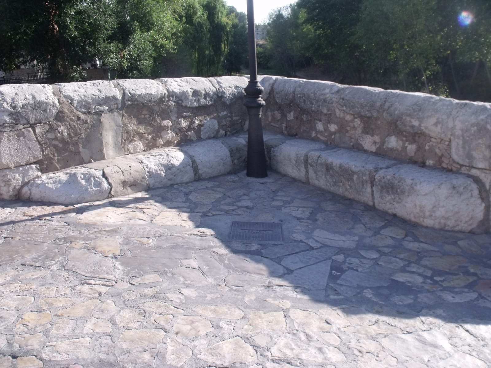 Banc corregut de pedra en un dels eixamplaments del Pont Vell, sobre la calçada empedrada