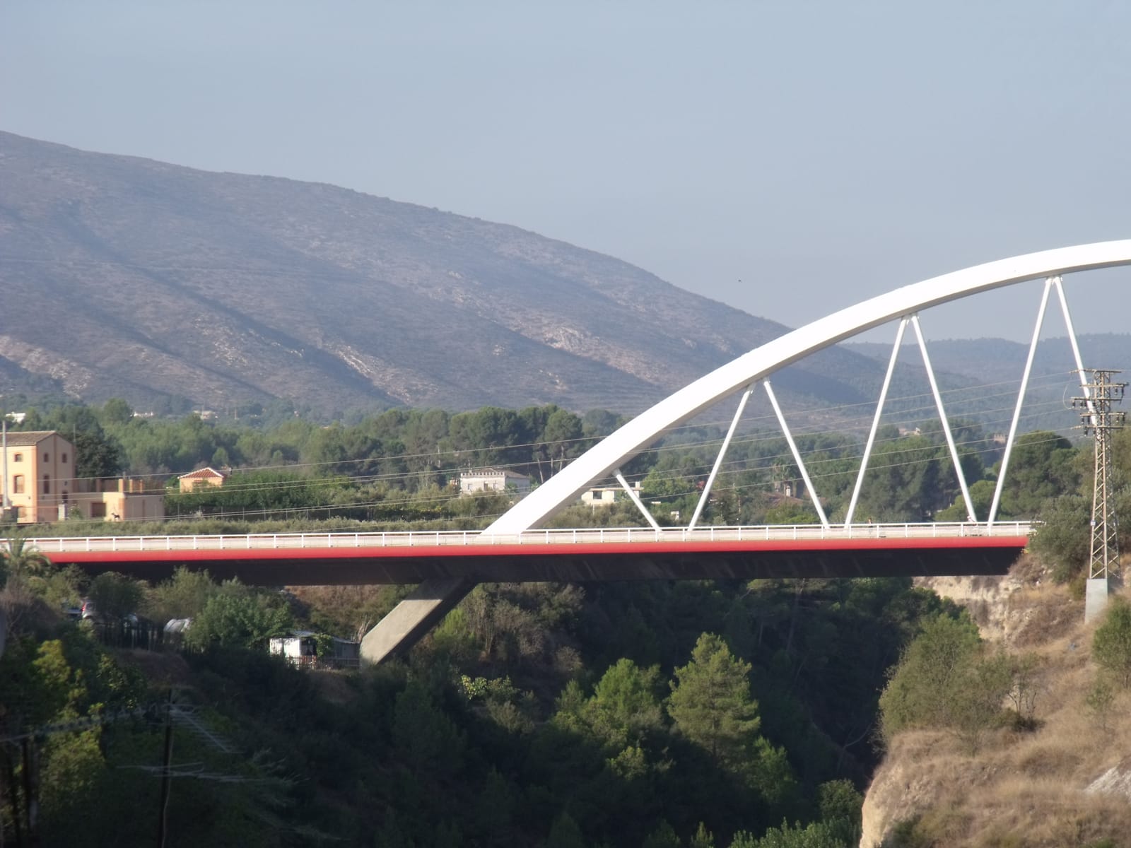 El pont del Salt del Bou, amb el seu gran arc blanc sobre el barranc del Clariano i la serra al fons